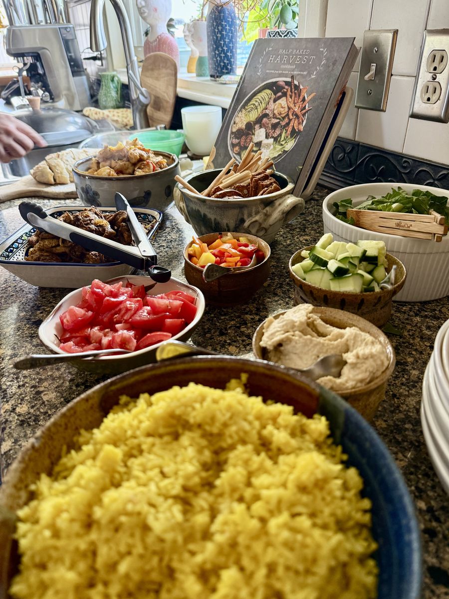 A buffet spread of saffron rice, tomatoes, hummus and sides